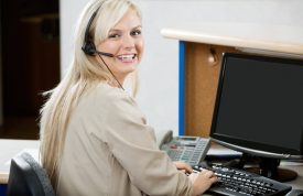 Cheerful Woman Using Computer At Reception Desk